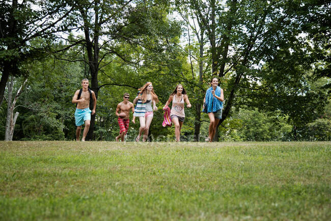Cinco amigos corriendo sobre hierba, vista frontal - foto de stock