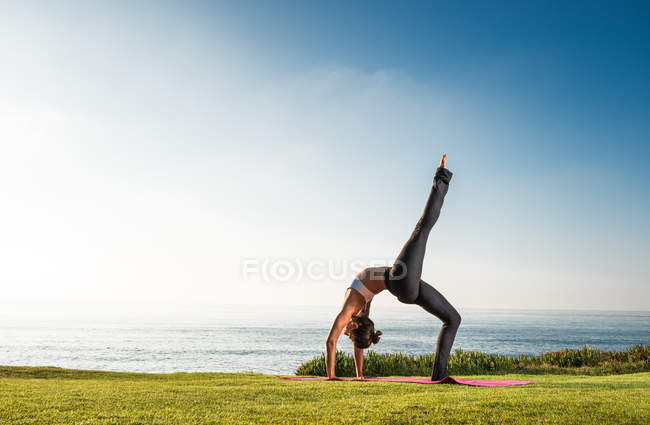 Mujeres en acantilado, en posición de yoga - foto de stock