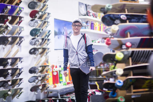 Portrait of young male skateboarder in skateboard shop — Stock Photo