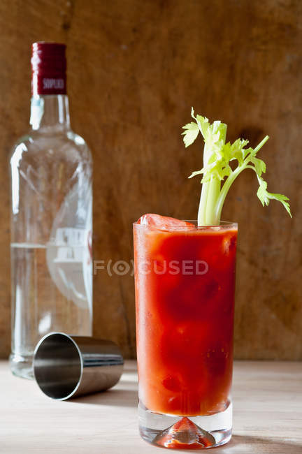 Bloody mary cocktail with celery and bottle on background — Stock Photo
