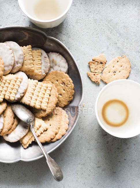 Top view of cookies in metal bowl and empty cups — Stock Photo