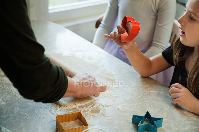Mother helping girls in kitchen to bake cookies — Stock Photo