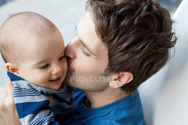 Father kissing baby son on cheek — Stock Photo