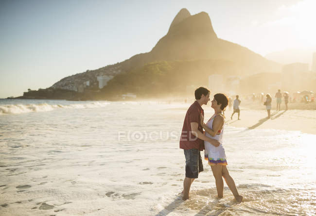 Junges paar umarmt sich bei sonnenuntergang, strand von ipanema, rio, brasilien — Stockfoto