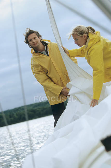 Casal levando para baixo vela no barco — Fotografia de Stock
