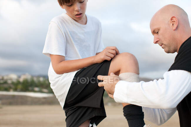 Hombre cuidando chico herido - foto de stock
