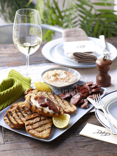 Tisch mit Saiblingsbrot vom Grill, Chorizo und weißer Bohnensauce — Stockfoto