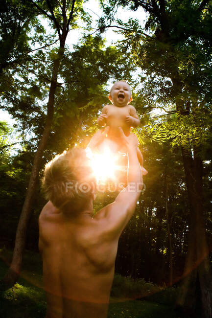 Отец поднимает девочку в лесу — стоковое фото