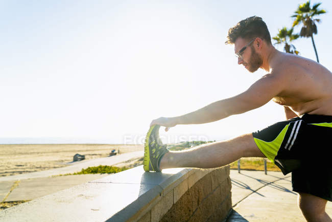 Young man exercising, stretching, outdoors — Stock Photo