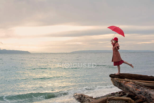 Женщина с зонтиком на прибрежной скале — стоковое фото