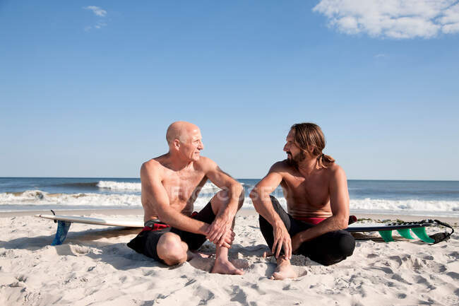 Two surfers talking on beach — Stock Photo