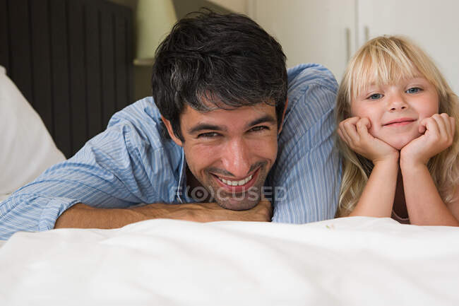 Padre e figlia sdraiati su un letto — Foto stock