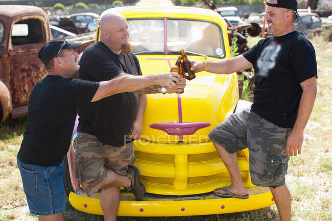 Men drinking beer by colorful car — Stock Photo