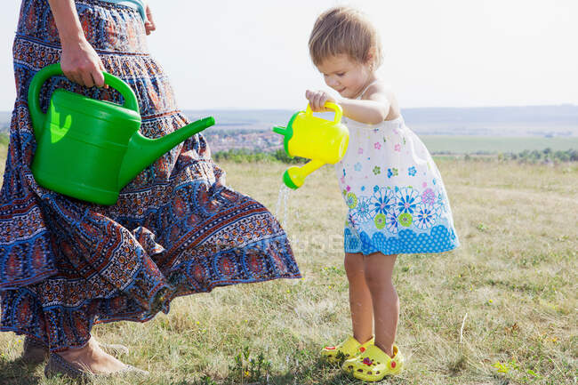 Mother and daughter watering plants — Stock Photo