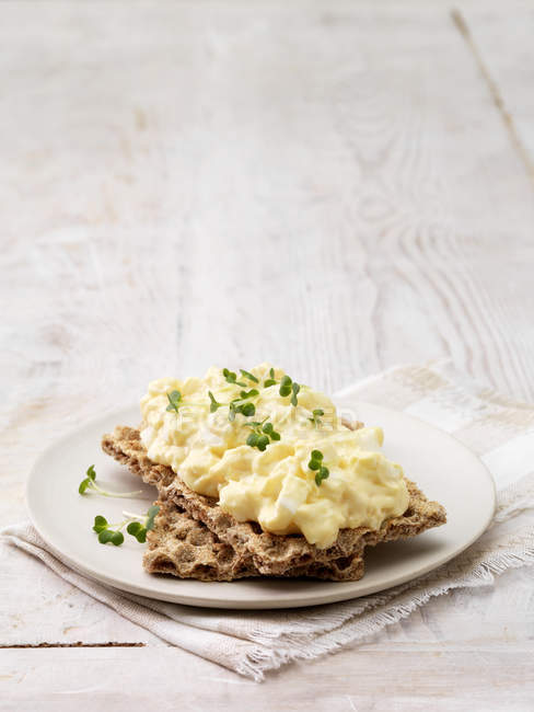 Egg mayonnaise garnished with cress on crackers on whitewashed wood surface — Stock Photo