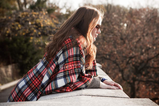 Girl with plaid blanket looking over wall — Stock Photo