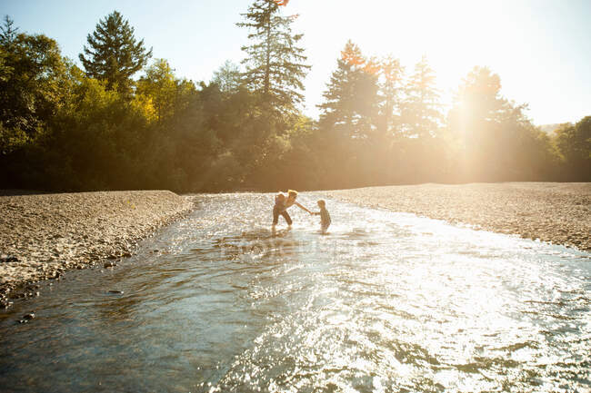 Мама з двома дітьми грає в річці — стокове фото