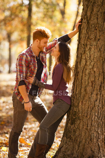 Romantisches junges Paar lehnt im Herbstwald an Baum — Stockfoto