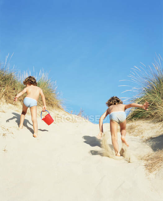 Twins running up a sand dune — Stock Photo
