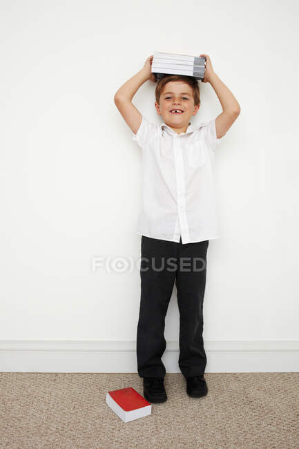 Schoolboy holding books on his head — Stock Photo