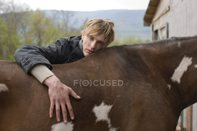 Mann stützt sich auf Pferd — Stockfoto