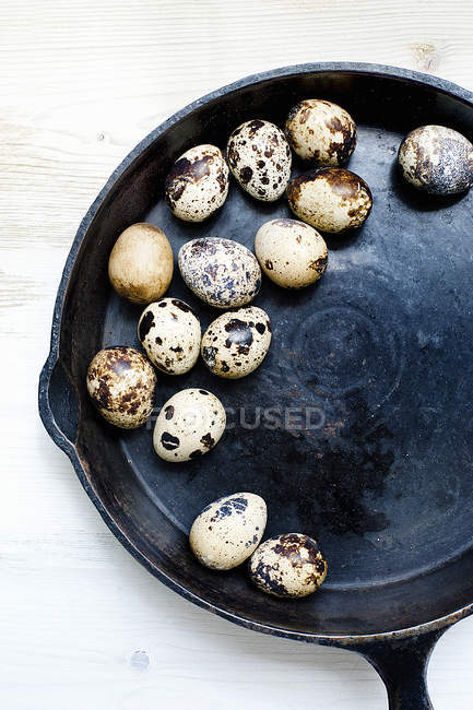 Quail eggs in frying pan on wooden table — Stock Photo