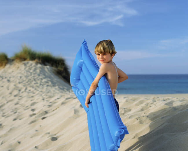 Хлопчик з надувним на краю піщаної дюни — стокове фото