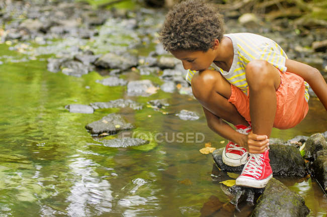Мальчик ищет рыбу в реке — стоковое фото