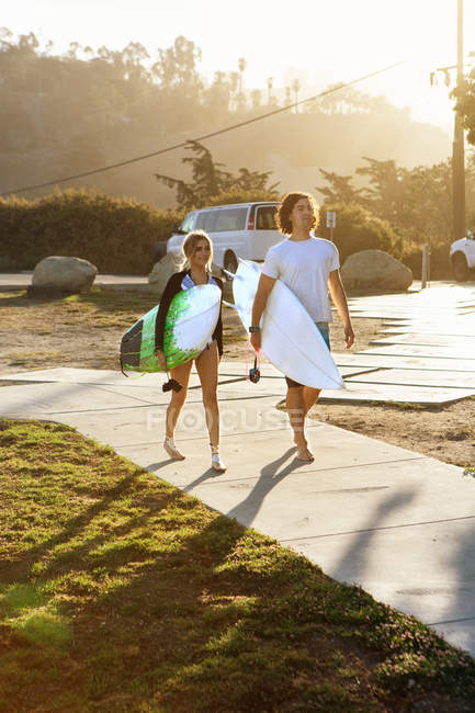Couple carrying surfboards, walking towards beach — Stock Photo