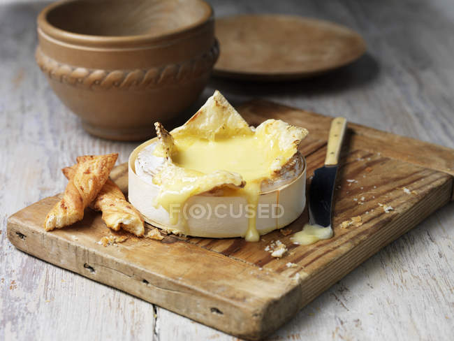 French baked camembert melted with bread sticks on wooden chopping board — Stock Photo