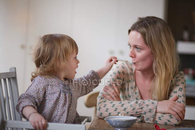 Daughter spoon feeding mother — Stock Photo