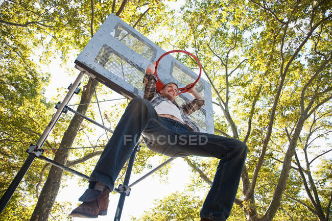 Mid adult man hanging from basketball hoop — Stock Photo