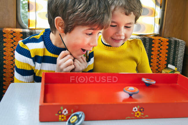 Two boys playing with spinning tops in caravan — Stock Photo