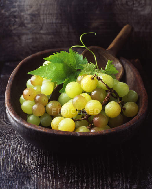 Bunch of green grapes in vintage wooden bowl — Stock Photo