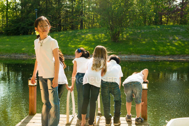 Niños en embarcadero junto al lago - foto de stock