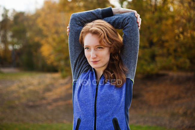 Young woman performing stretches in park — Stock Photo