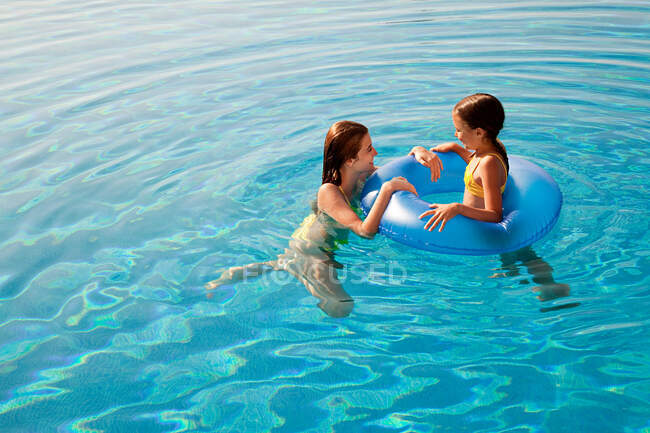 Chicas con anillo inflable en la piscina - foto de stock