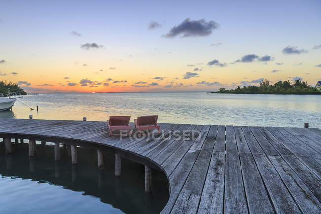 Two sun loungers on waterfront boardwalk at sunset, St. Georges Caye, Belize, Central America — Stock Photo
