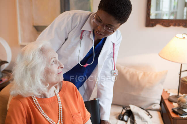 Senior woman and doctor in home — Stock Photo