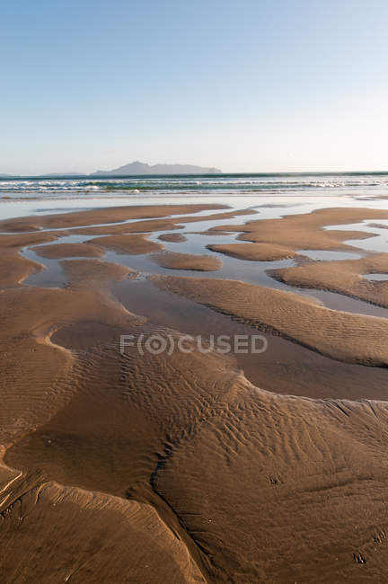 Вода делает шаблоны в песке на пляже — стоковое фото