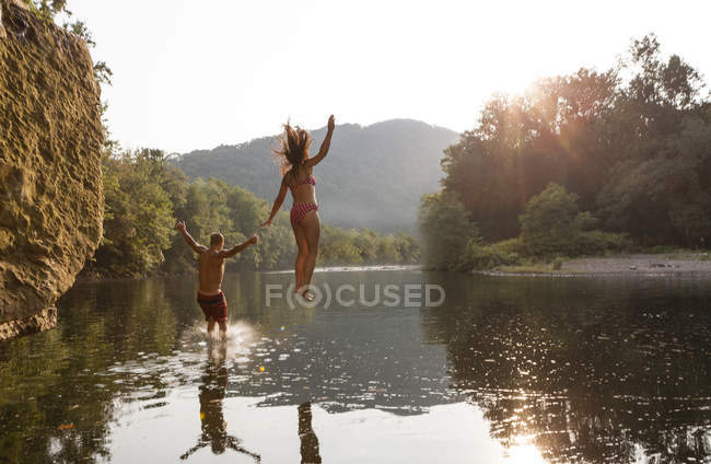 Junges Paar springt in Fluss, Hamburg, Pennsylvania, USA — Stockfoto