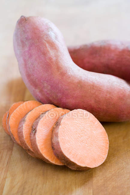 In Scheiben geschnittene und ganze Süßkartoffeln, Nahaufnahme — Stockfoto