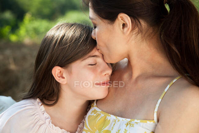 Portrait of mother kissing daughter on forehead — Stock Photo