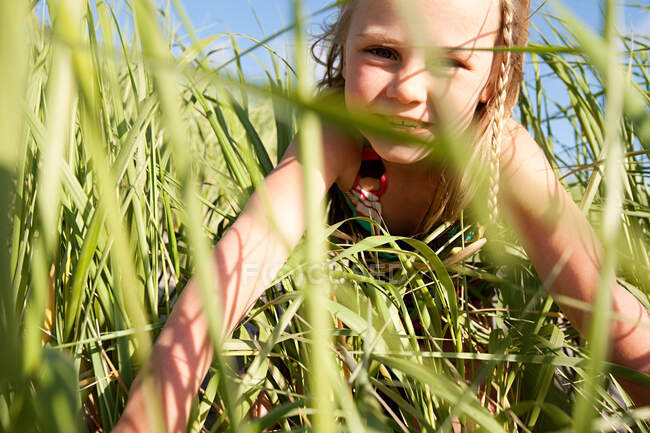 Menina olhando através de grama longa — Fotografia de Stock