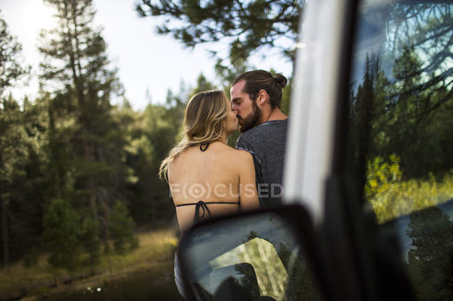 Rear view of romantic young couple kissing at riverside, Lake Tahoe, Nevada, USA — Stock Photo