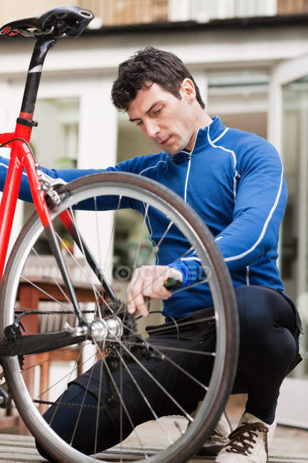 Hombre adulto medio ajustando rueda de bicicleta - foto de stock