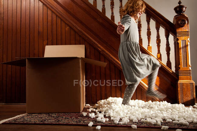 Girl playing with packing material from cardboard box — Stock Photo