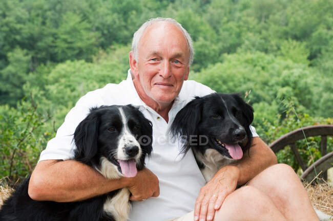 Uomo anziano con due cani in braccio, ritratto — Foto stock