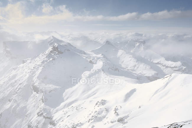 Catena montuosa innevata con nuvole nebbiose — Foto stock