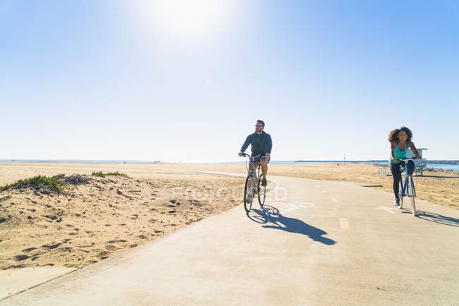 Pareja de ciclismo a lo largo del sendero en la playa - foto de stock